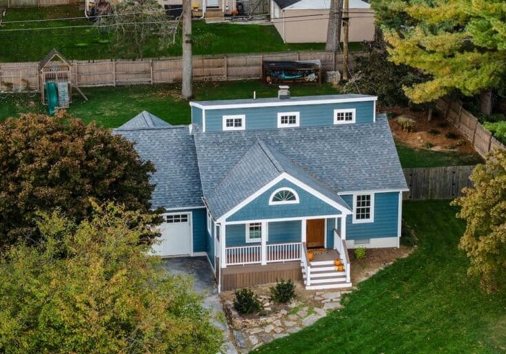 Finished deck and siding installation in Coatesville, PA. The house has a new blue exterior, crisp white window trim, and a multi-level brown deck.